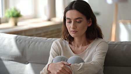 Грустная девушка сидит, обхватив ноги